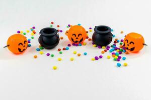 Halloween, pumpkins, colored sprinkles, cauldron, cauldron, on white background. Selective focus. photo