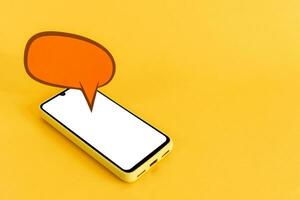 Paper speech bubbles and smart phone with blank screen, on yellow background. Isometric view. photo
