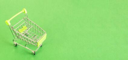 Top view of Empty shopping cart on green background, buy and sell concept. photo