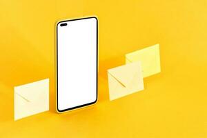 inteligente teléfono y sobres en amarillo antecedentes. en línea comunicación concepto. foto