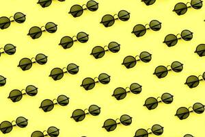 Black sunglasses pattern on pastel yellow background. Minimal summer concept. photo