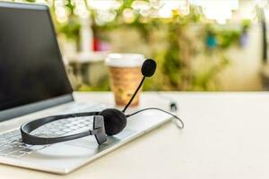 Headset with microphone on keyboard computer laptop, on desktop. Call center support concept. photo