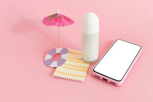 Assembling the skin care cream bottle container, beach umbrella and smart phone on pink background. Summer travel and vacation concept. Beauty and cosmetics concept. photo