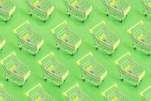 Top view of pattern Empty shopping cart on green background, buy and sell concept. photo