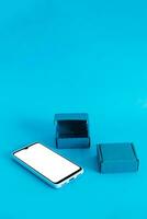 Isometric view of mobile phone and two boxes on light blue background. Shopping online.. photo