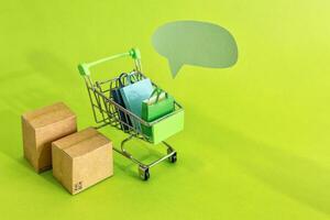 Cardboard boxes or paper boxes in shopping cart on green background. Online shopping and delivery service concept. photo