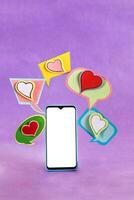 Mobile phone and dialogue bubbles with hearts. Dating app concept. photo