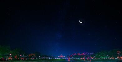 a park with a tree and a moon in the sky photo