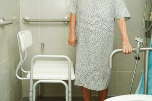 Asian elderly old woman patient use toilet support rail in bathroom, handrail safety grab bar, security in nursing hospital. photo