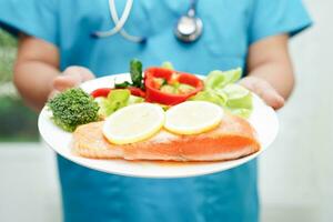 Asian Nutritionist holding healthy food for patient in hospital, nutrition and vitamin. photo