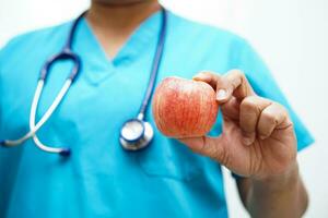 asiático nutricionista participación manzana sano comida para paciente en hospital, nutrición y vitamina. foto