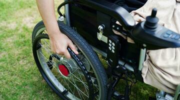 Asian elderly woman disability patient sitting on electric wheelchair in park, medical concept. photo