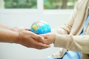 Bangkok, Thailand April 1, 2023 Asian elderly woman patient holding globe in hand at hospital. photo