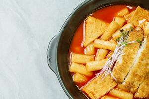 tteokbokki, un picante coreano plato de Cerdo chuletas, verduras, y pescado pasteles servido en un negro lámina. foto