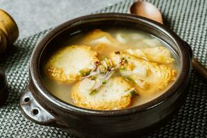 coreano pescado pastel sopa servido en un negro arcilla maceta foto