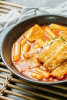 Tteokbokki, a spicy Korean dish of pork cutlets, vegetables, and fish cakes served on a black plate. photo