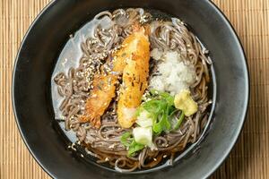 A summer dish of cold wheat noodles with fried shrimp in a black bowl photo