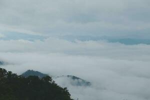 Mountain range with visible silhouettes through the morning blue fog. photo