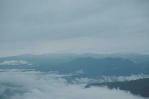 Mountain range with visible silhouettes through the morning blue fog. photo