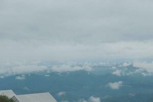 hermosa panorámico ver de niebla y nubes en distante capas montañas rango con azul cielo en Mañana foto