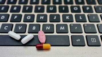 Various types of drugs, placed on a laptop keyboard photo