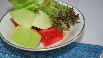 watermelon, melon, papaya and lettuce on a white plate photo