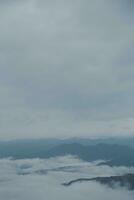 Mountain range with visible silhouettes through the morning blue fog. photo