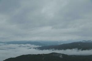 Mountain range with visible silhouettes through the morning blue fog. photo