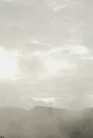 Mountain range with visible silhouettes through the morning blue fog. photo