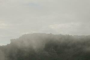 Mountain range with visible silhouettes through the morning blue fog. photo