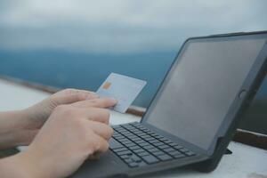 online payment, young woman holding credit card and typing on laptop photo