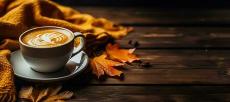 Coffee cup with autumn leaves and knitted sweater on wooden table photo