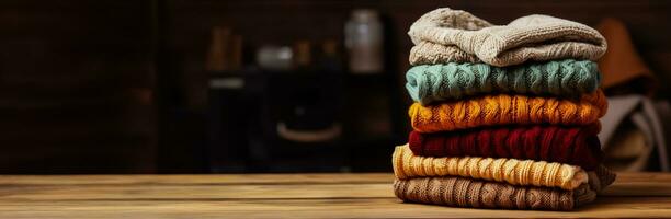 Pile of knitted winter clothes on wooden background sweaters knitwear photo