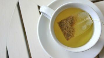 Healthy chamomile tea is poured into a white cup photo