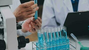 médico o científico investigador o hombre médico mirando a un prueba tubo de claro solución en un laboratorio video