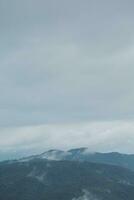 Mountain range with visible silhouettes through the morning blue fog. photo