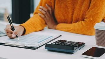 Asian Business woman using calculator and laptop for doing math finance on an office desk, tax, report, accounting, statistics, and analytical research concept video