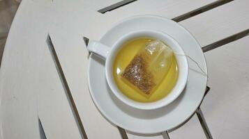 Healthy chamomile tea is poured into a white cup photo