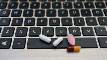 Various types of drugs, placed on a laptop keyboard photo