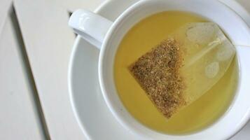 Healthy chamomile tea is poured into a white cup photo