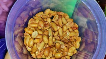 Fresh roasted peanuts, salt and oil on glass jar photo