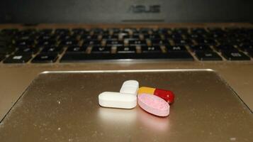 Various types of drugs, placed on a laptop keyboard photo