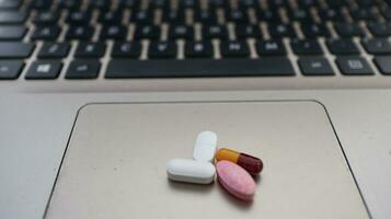 Various types of drugs, placed on a laptop keyboard photo