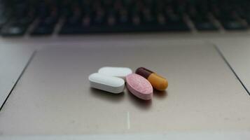 Various types of drugs, placed on a laptop keyboard photo