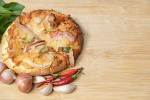 Pizza on wooden board with fresh peppers and basil with garlic on copy space background photo