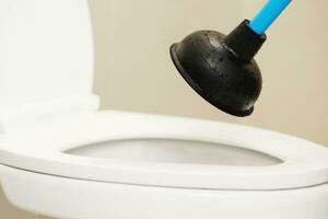 Serviceman repairing toilet with hand plunger. Clogged toilet. photo