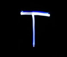 T Tango alphabet hand writing blue light  over black background. photo