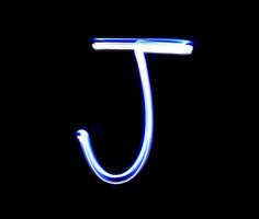 J Jimmy alphabet hand writing blue light  over black background. photo