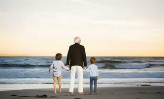 Grandfather walking with grandchildren at beach. Concept of grandfather day, grandparents day photo