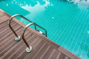 Swimming pool water with stair and wood floor. photo